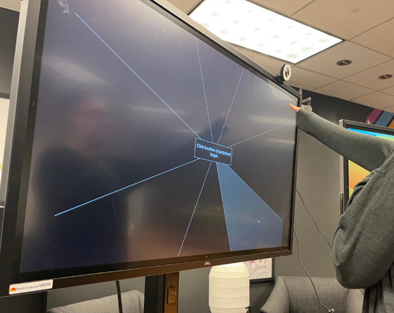 A person pointing at a large screen in an office
