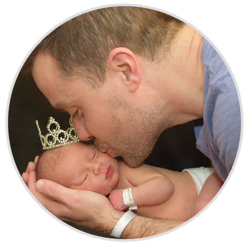 A man kissing a baby with a crown on his head