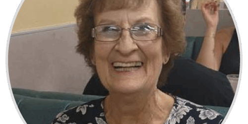 stories-roberta A woman with glasses sitting on a couch