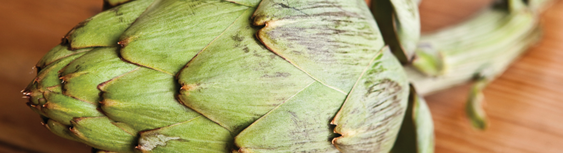 A green artichoke on a wooden surface