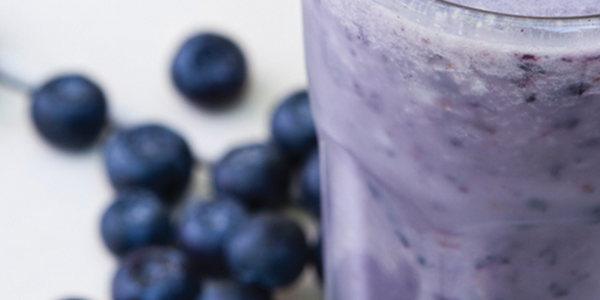 bluenana A blueberry smoothie in a tall glass next to blueberries