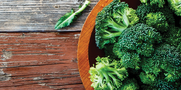 broccoli A wooden bowl filled with broccoli on top of a wooden table