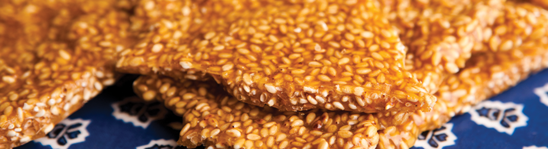 A close up of sesame seed crackers on a blue and white cloth