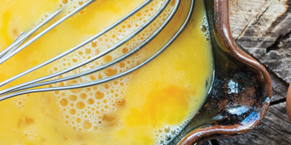 egg A bowl with eggs and a whisk on a wooden table