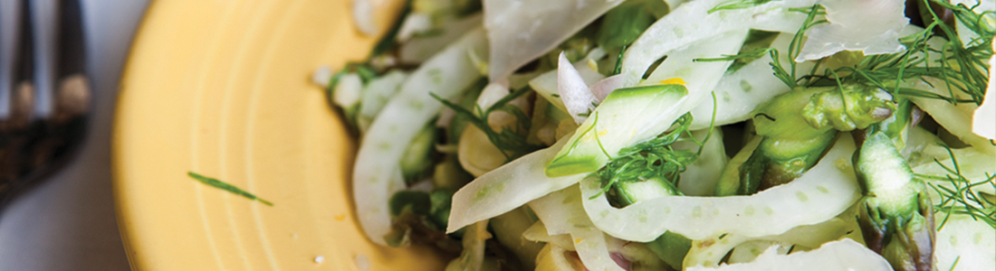 A yellow plate topped with a salad and a fork