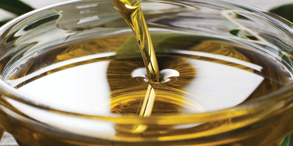 A glass of olive oil being poured into it