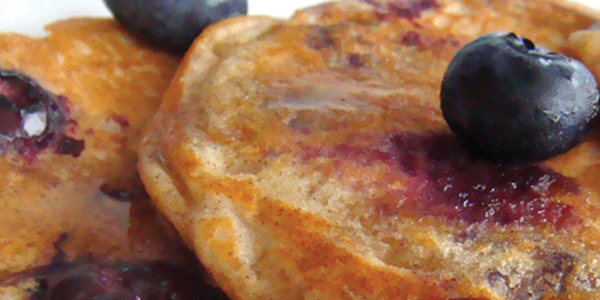 A white plate topped with pancakes covered in blueberries
