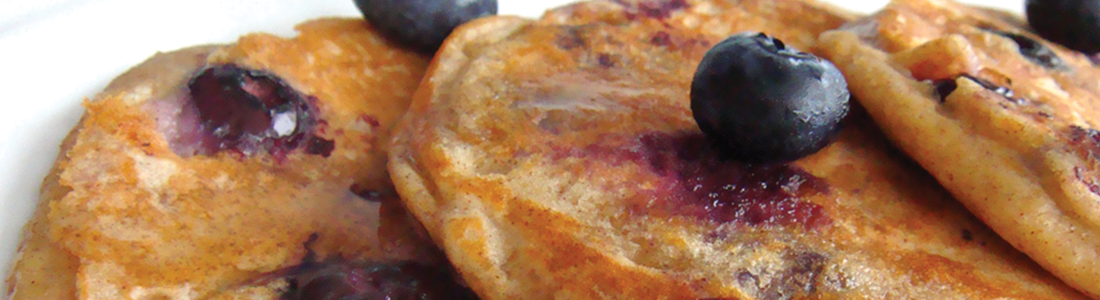 A white plate topped with pancakes covered in blueberries