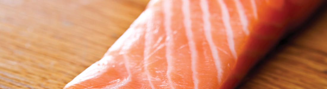 A piece of salmon sitting on top of a wooden table