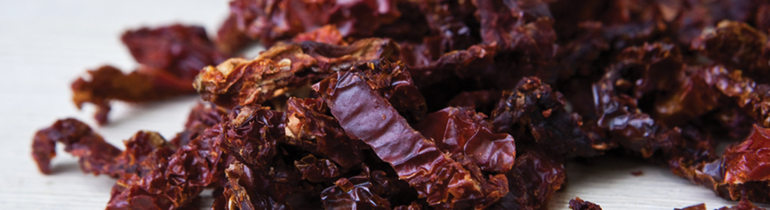 A pile of dried red raisins sitting on top of a table