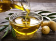 Olive oil being poured into a bowl of olives