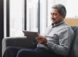 A man sitting on a couch looking at a tablet