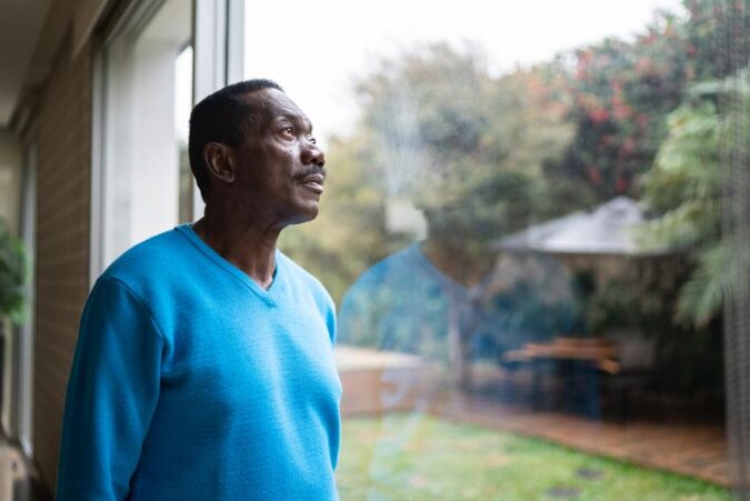 A man in a blue sweater looking out a window