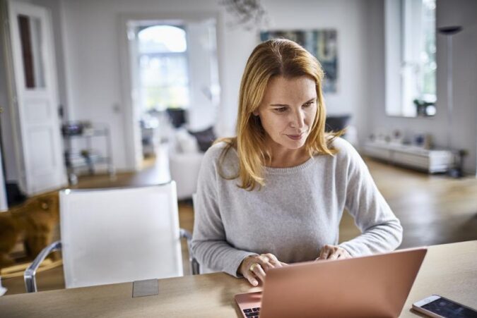 A woman sitting at a table using a laptop computer