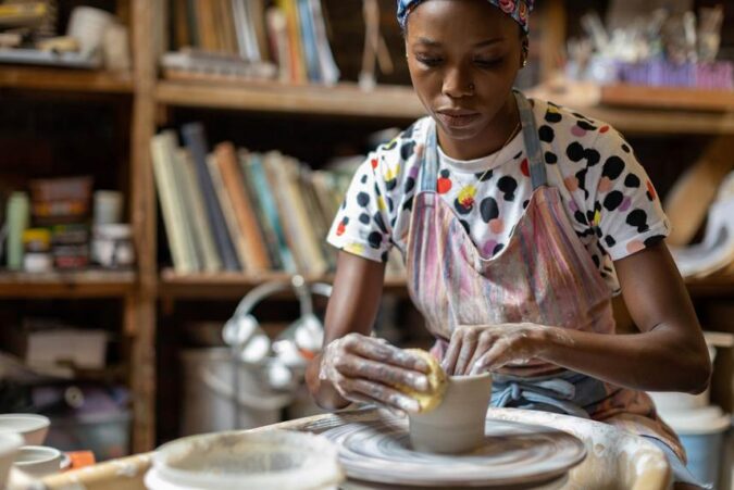 A woman is making a vase out of clay