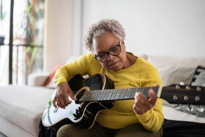 A woman sitting on a couch playing a guitar