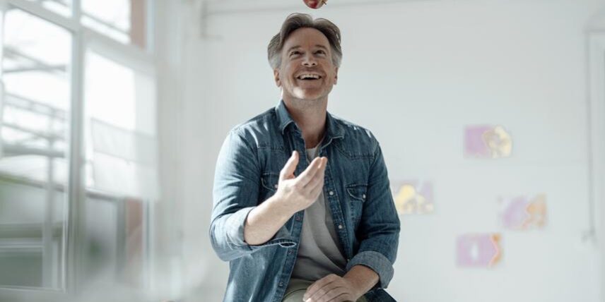 A man sitting on top of a table with an apple on top of his head