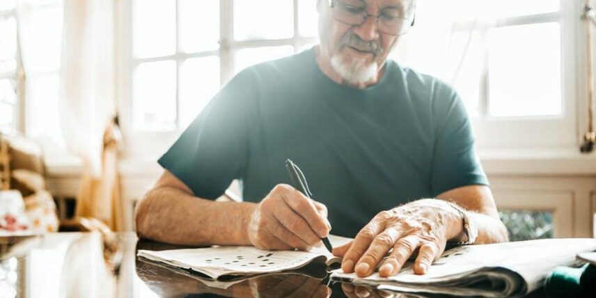 DoCrosswordsWork_1270285125_5 A man sitting at a table writing on a piece of paper