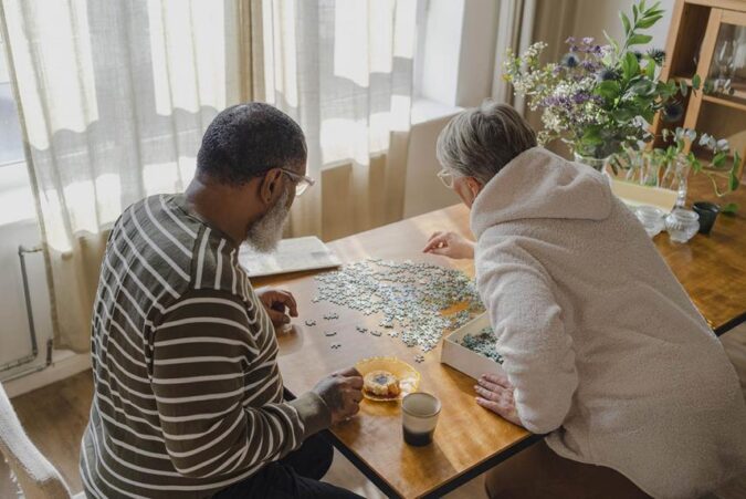 A man and woman sitting at a table playing a game