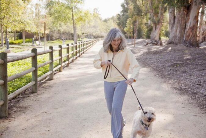 A woman walking a dog on a leash