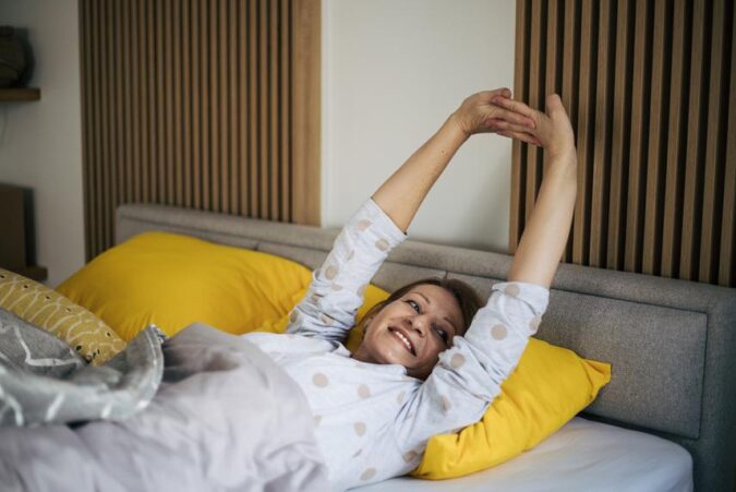 A woman laying on a bed with her arms in the air