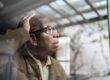 A man with glasses looking out a window