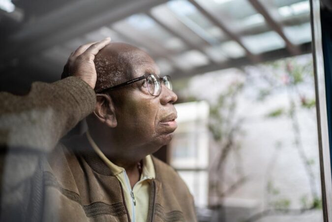 A man with glasses looking out a window