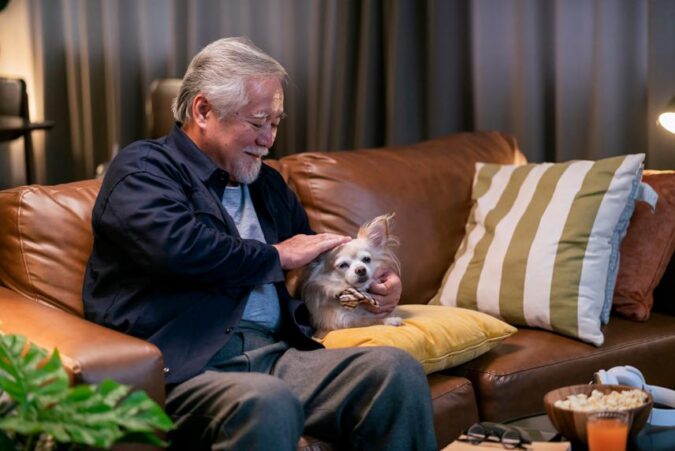 A man sitting on a couch holding a small dog