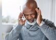 A man with a bald head holding his hands to his ears